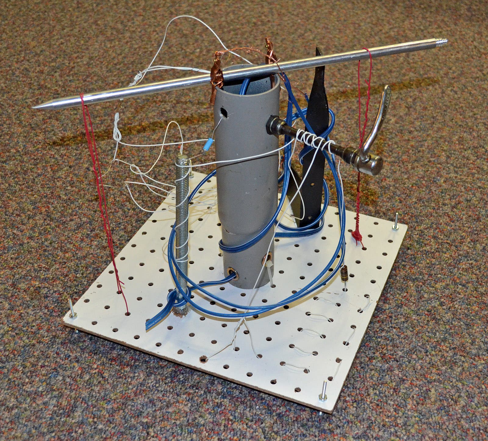Photo of a sculpture with a vertical metal cylinder, wires, knitting needle, etc.