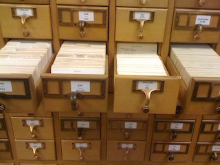 Photograph of a library card catalog with one row of open drawers.