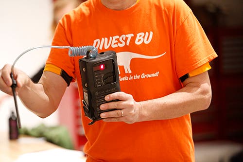 Photo of person holding a small box with controls and display, and a small probe connected to the box with a coiled tube.
